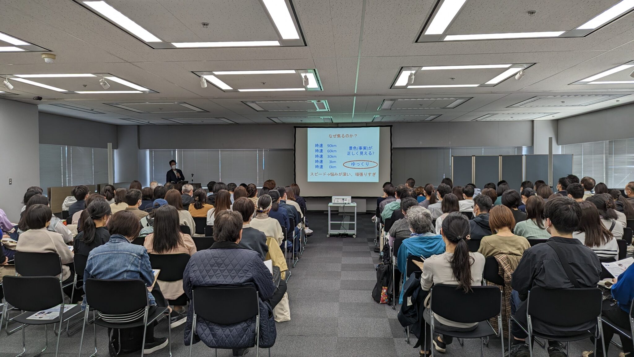 新宿の「不登校生のための学校相談会」で行われた特別講演。スクリーンと客席の様子